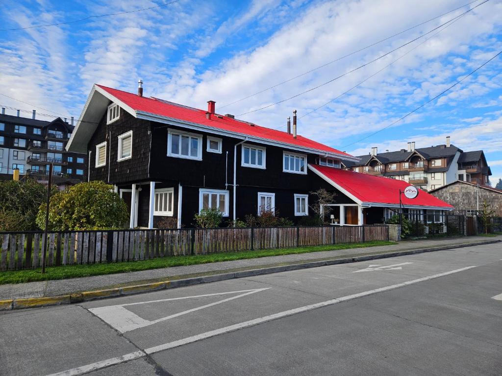 a black house with a red roof on a street at Casa Ellies Hotel Boutique in Puerto Varas