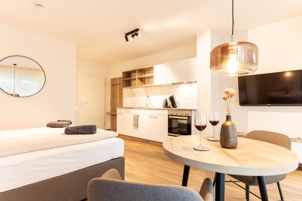 a living room and kitchen with a table and a bed at Kapfwald Appartements in Bad Dürrheim