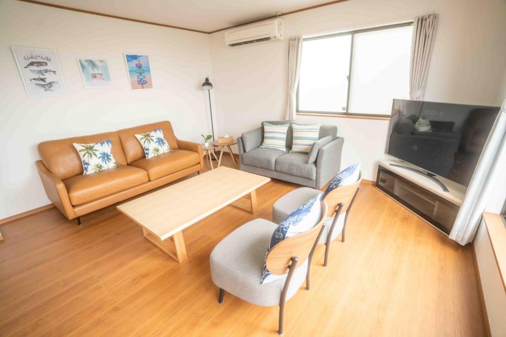 uma sala de estar com um sofá, uma mesa e uma televisão em White Terrace D - Vacation STAY 44940v em Nakadomari