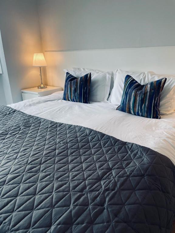 a large bed with blue pillows on top of it at Watts Lodge in Bicester