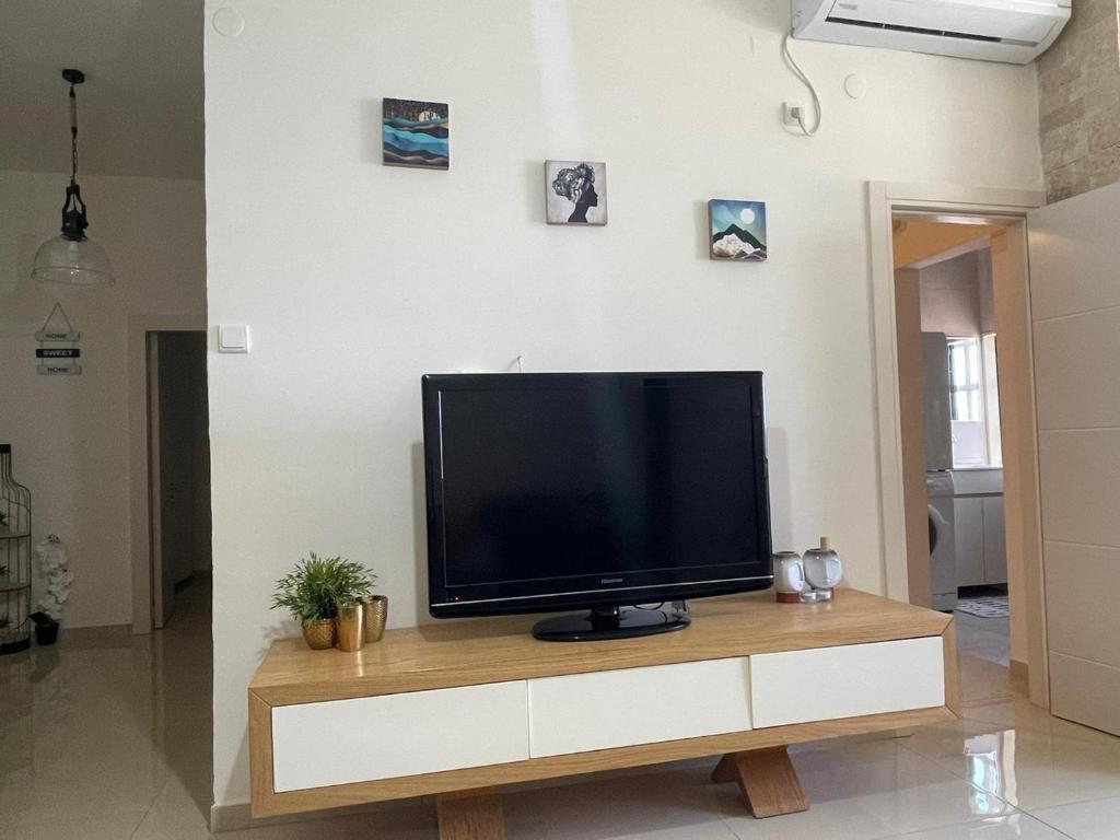 een flatscreen-tv bovenop een houten entertainmentcentrum bij Estrela Mares Haifa in Haifa