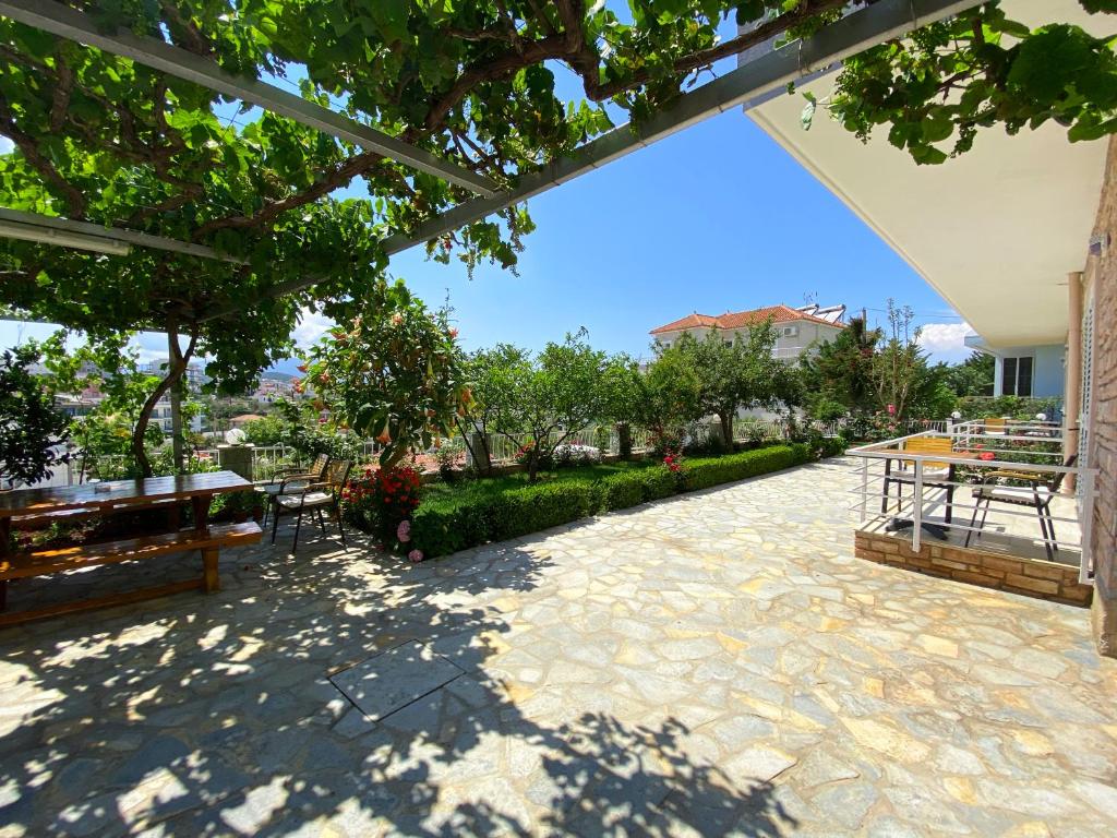 eine Terrasse mit Tischen, Bänken und Bäumen in der Unterkunft Villa Paja in Ksamil