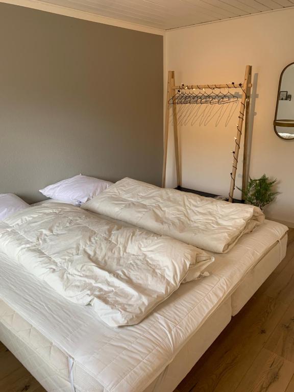 an unmade bed with white sheets in a bedroom at Huset ved søen tæt på Herning og MCH og boxen 90 m2 in Sunds