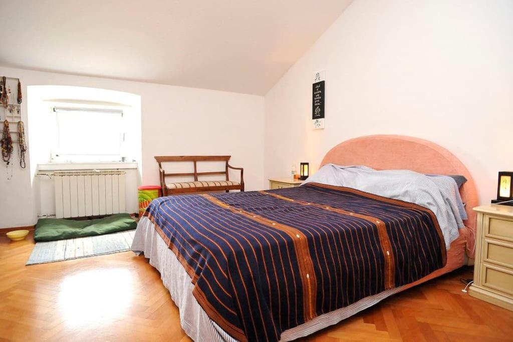 sypialnia z dużym łóżkiem i oknem w obiekcie Spacious Attic Apartment Kandler w Trieście