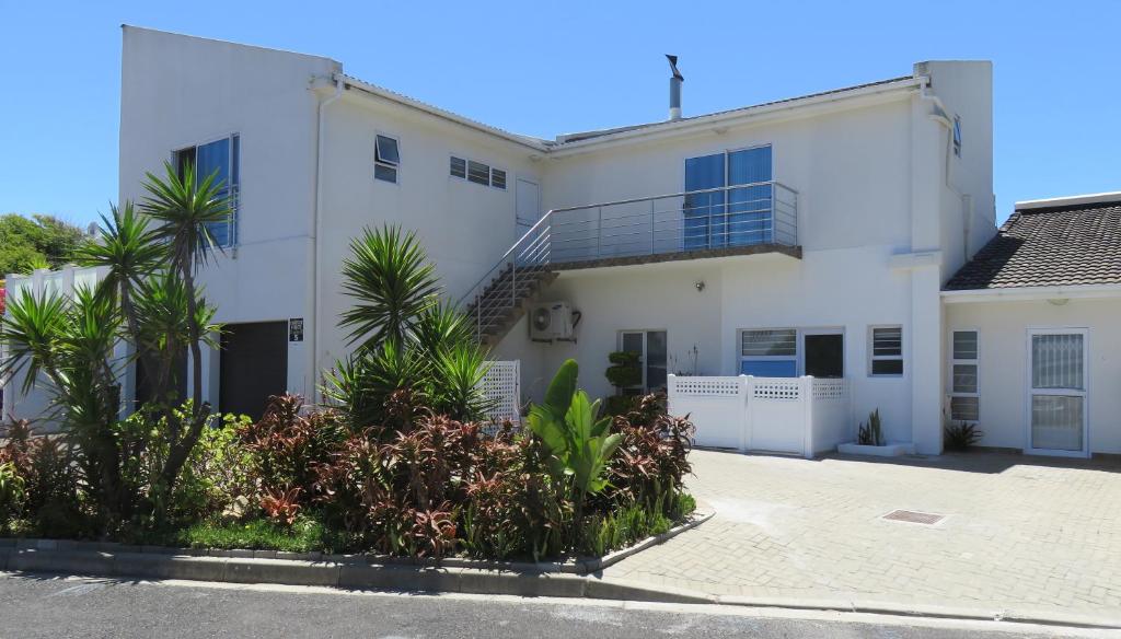 a white house with palm trees in front of it at Pro Moni's Guesthouse in Muizenberg