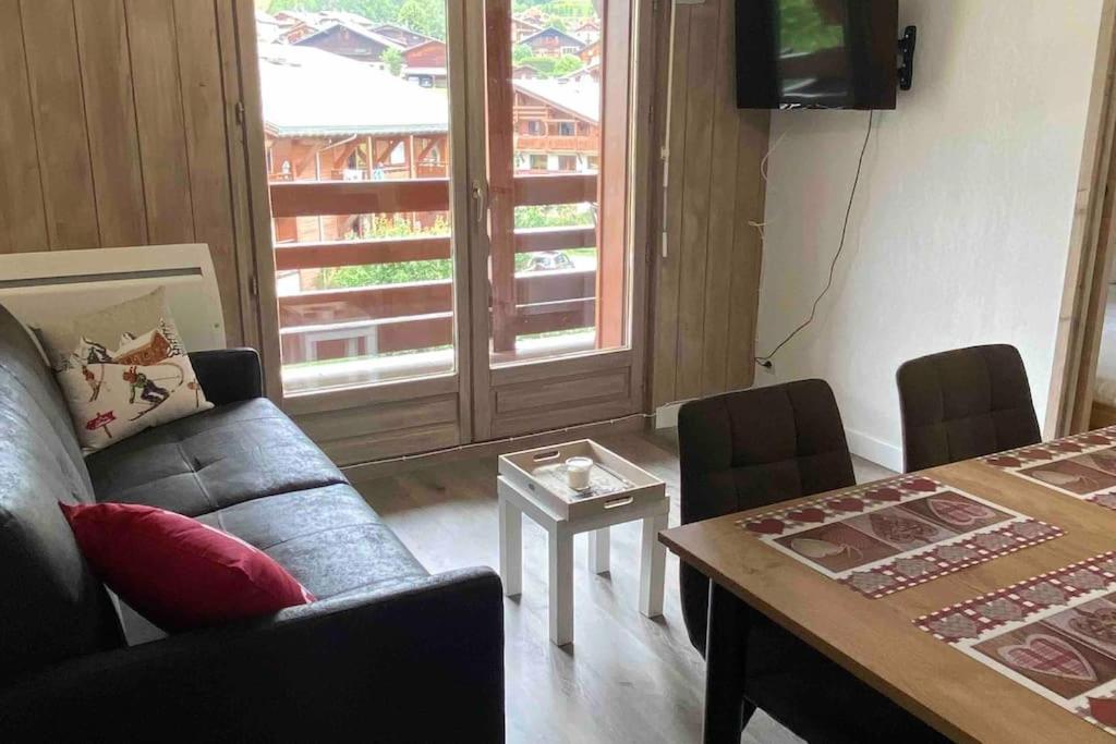 un salon avec un canapé et une table avec des chaises dans l'établissement Praz sur Arly - proche des pistes et de Megève, à Praz-sur-Arly