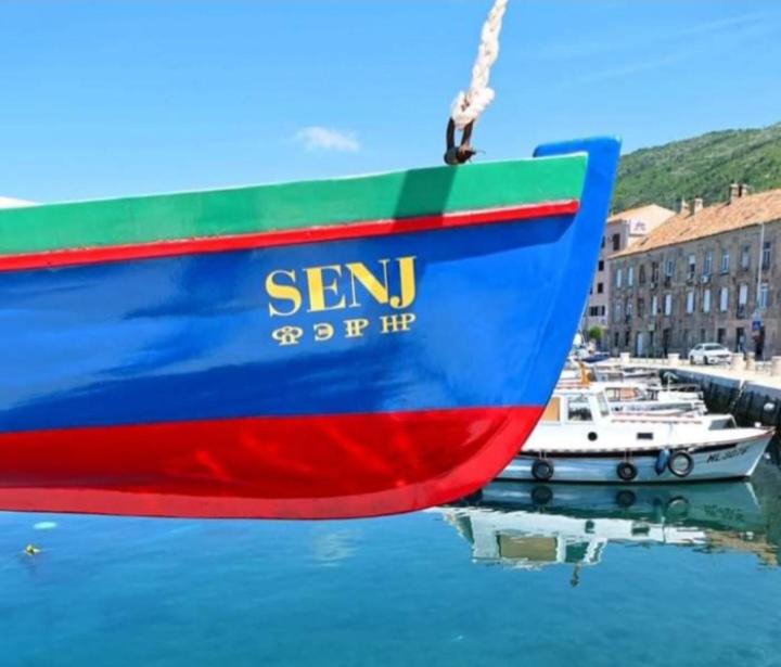 un barco azul y rojo sentado en el agua en App VITO, en Senj
