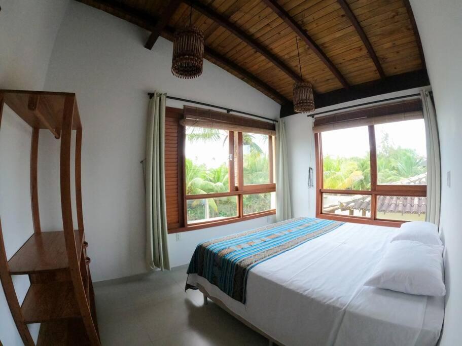 ein Schlafzimmer mit einem großen Bett und zwei Fenstern in der Unterkunft VILA BOMBACA - 100m da praia in Barra Grande