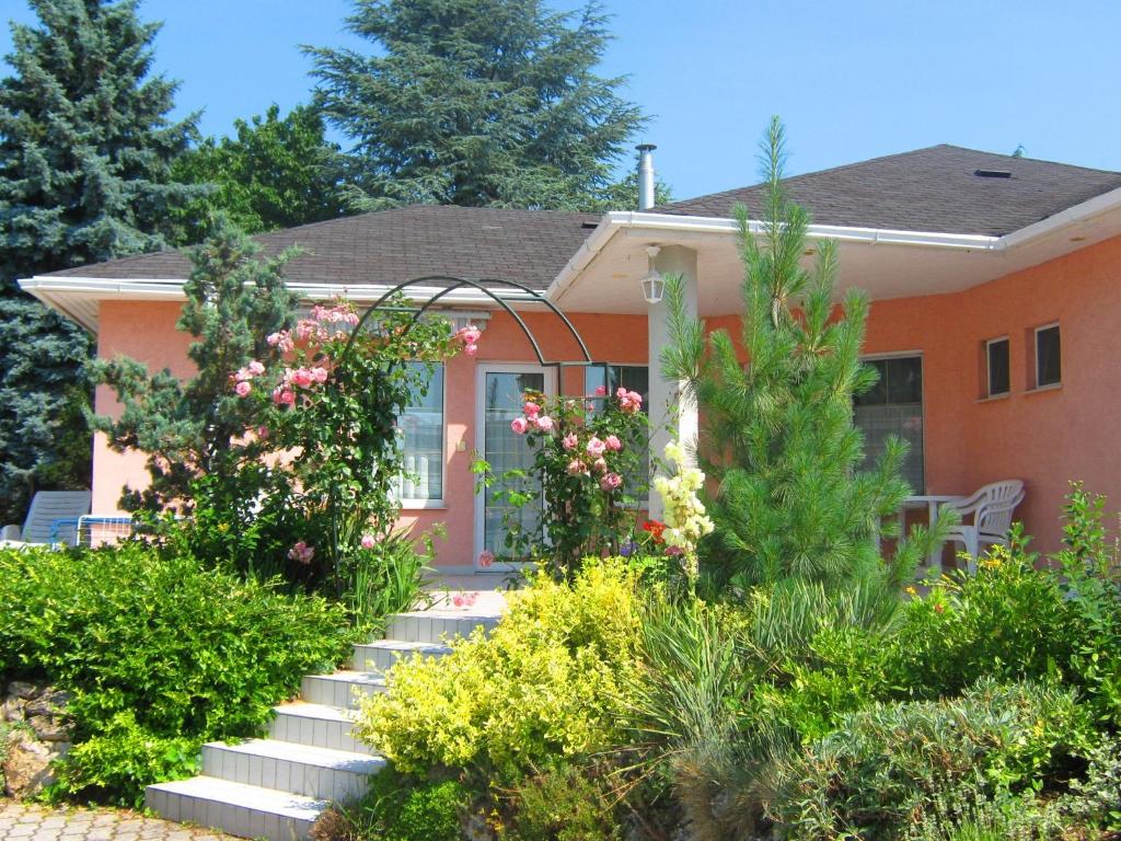 a house with a garden with flowers in front of it at Fészek Apartmanház in Vonyarcvashegy