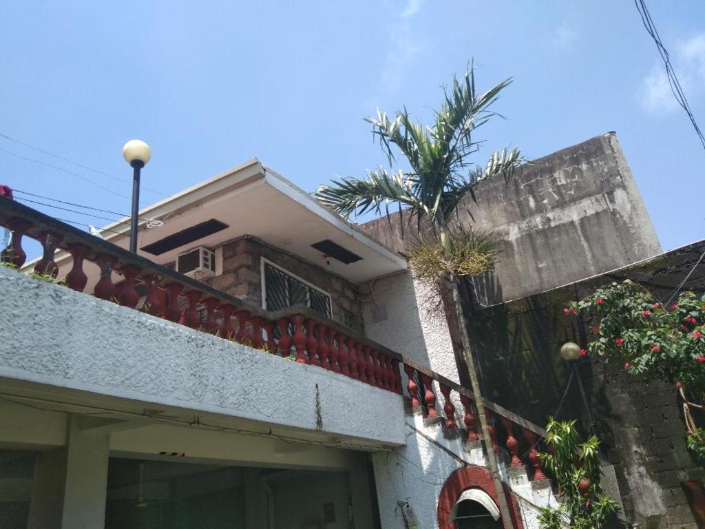 een huis met een balkon en een palmboom bij The Terrace Room in Manilla