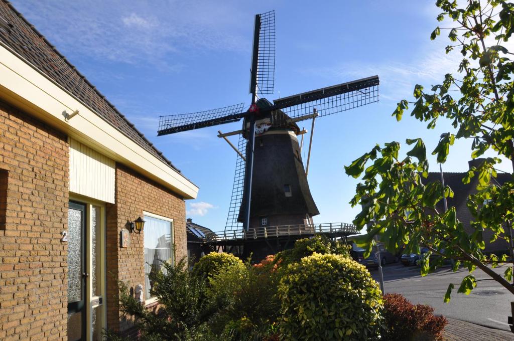 um moinho de vento em frente a um edifício e a uma casa em Bed en Breakfast Molenzicht em Nootdorp