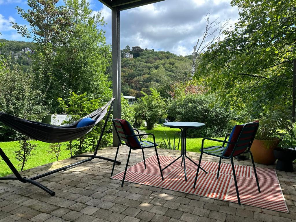 a patio with a hammock and two chairs and a table at Plaisances, les plaisirs du bord de Meuse - Chambre d'hôtes avec baignoire spa in Profondeville