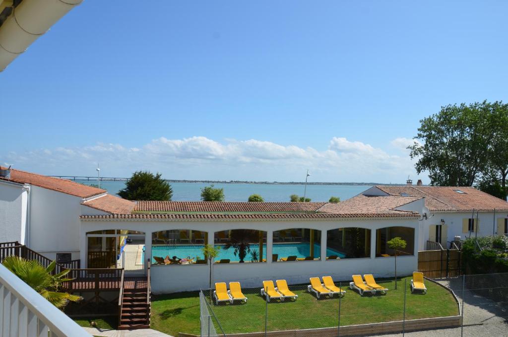 a house with a swimming pool and yellow lounge chairs at Hotel et Spa Les Cleunes Oléron in Saint-Trojan-les-Bains