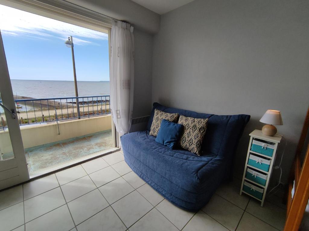 ein Wohnzimmer mit einem blauen Sofa und Meerblick in der Unterkunft Studio 2 Personnes -- Vue Port de Comberge ! in Saint-Michel-Chef-Chef