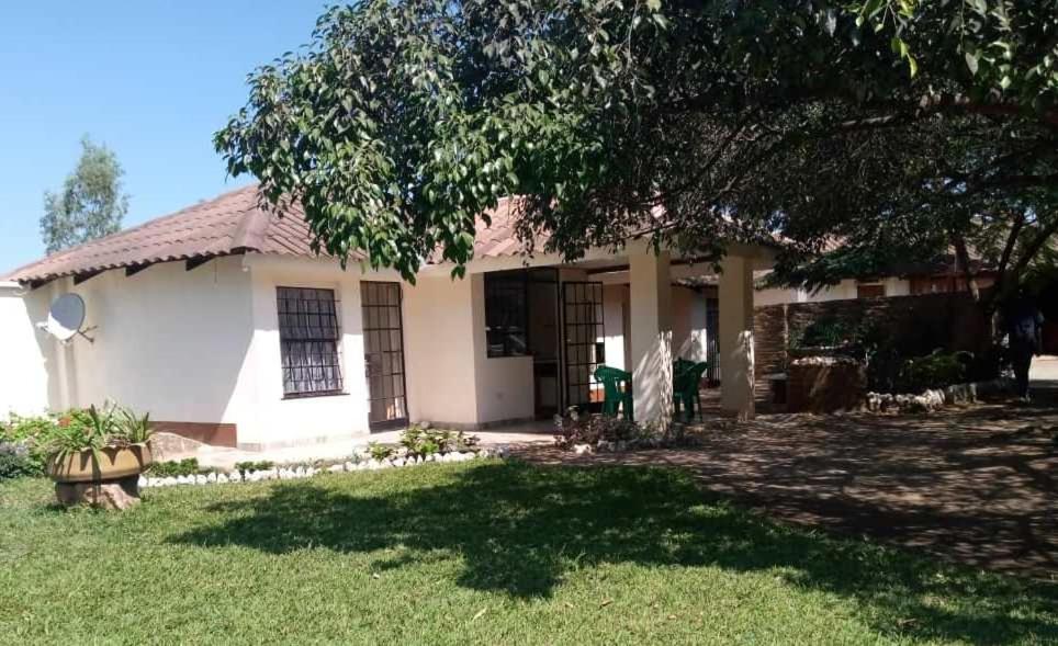 een wit huis met een boom in de tuin bij Sonke Ball House(Nyumba Yangati Mpira) in Nyambadwe