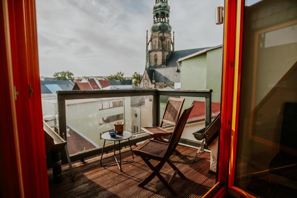 d'un balcon avec deux chaises, une table et une tour d'horloge. dans l'établissement traumhaftes Apartment am Dom mit großer Dachterrasse, à Zwickau