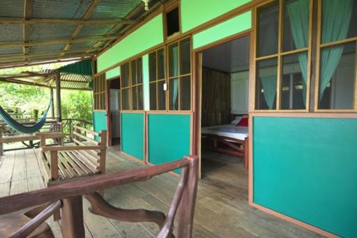 a porch of a house with benches and a hammock at Cabinas vista isla del caño corcovado in Drake