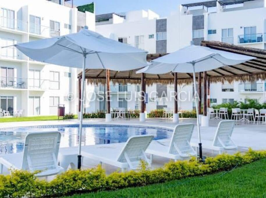 a pool with chairs and umbrellas next to a building at Departamento Acapulco Diamante - 2 habitaciones in Acapulco