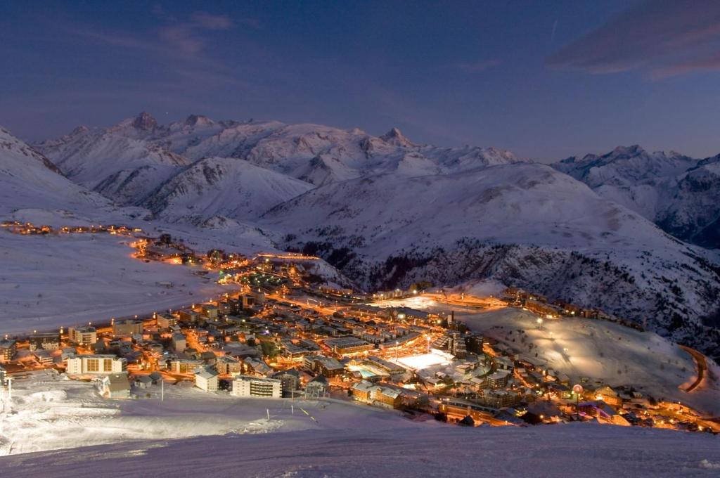 een stad in de sneeuw 's nachts met bergen bij L'ALPE D'HUEZ Appartement 4 couchages idéalement situé in Huez
