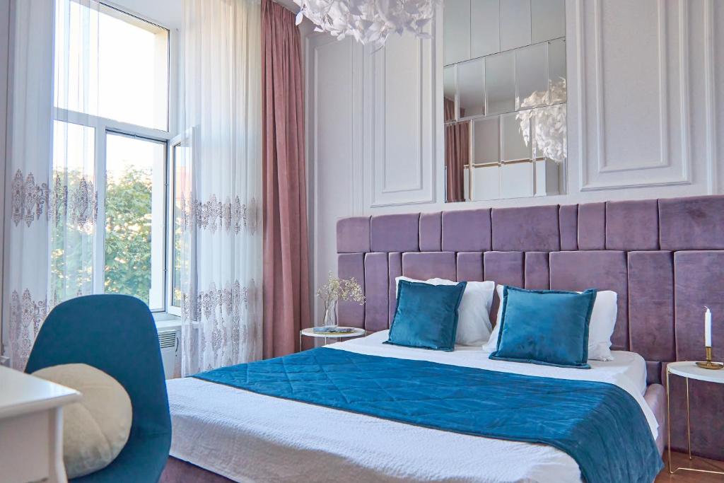 a bedroom with a large bed with a purple headboard at Elegant Lux Apartment in central square in Mukacheve