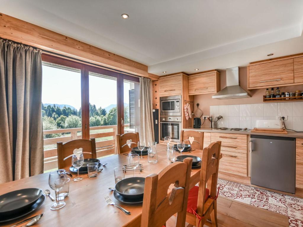 une cuisine avec une table en bois, des chaises et une grande fenêtre dans l'établissement Appartement Magnifique aux Gets - T3 Rénové pour 6 Pers, Proche Centre et Pistes - FR-1-685-60, aux Gets