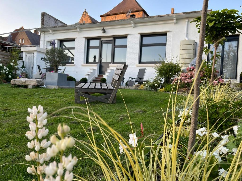 a white house with a yard with flowers at Le petit paradis in Cassel