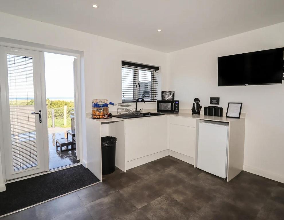 a kitchen with white cabinets and a flat screen tv at terfyn hall holiday apartment 3 stargazer in Prestatyn