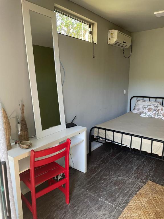 a room with a bed and a mirror and a red chair at Vila Drávida in Iporanga