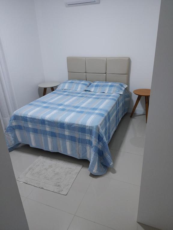 Una cama con una manta de cuadros azul y blanco en un dormitorio en Apto novo e bem localizado em Porto Belo - SC, en Porto Belo