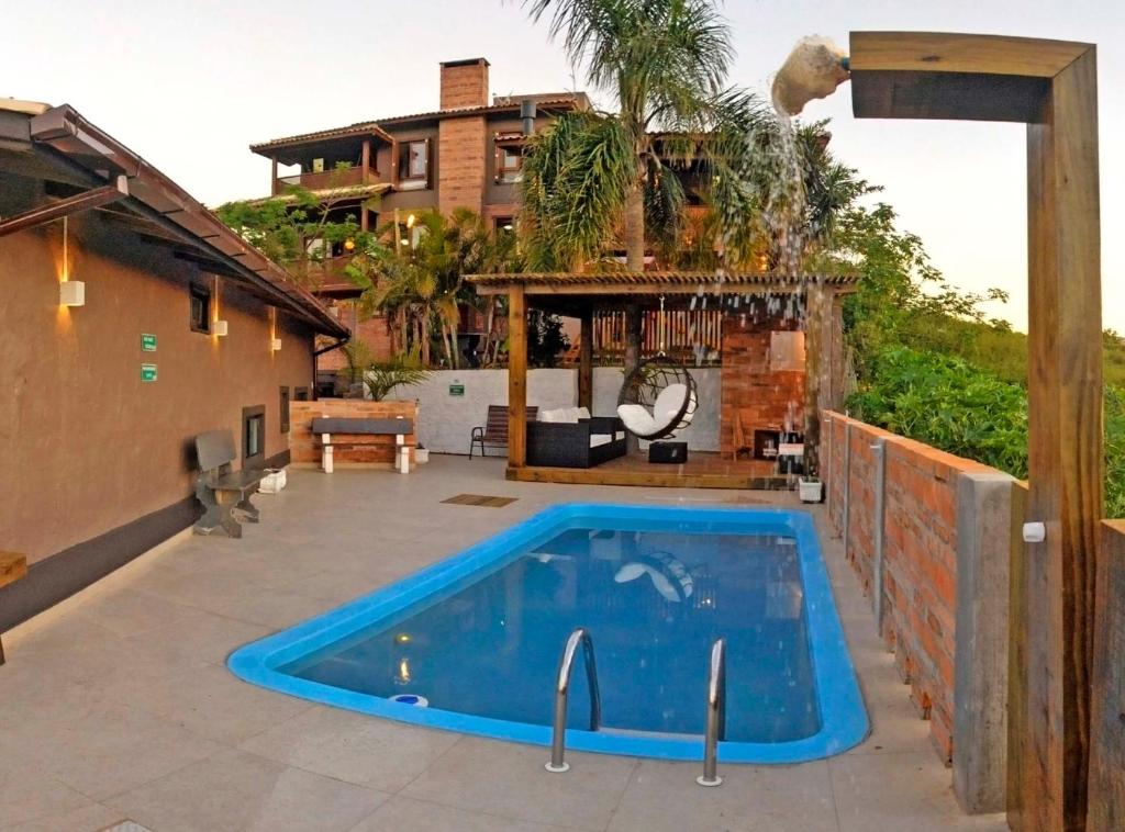 a swimming pool on a patio next to a house at Bangalôs do Rosa-Praia do Rosa in Imbituba