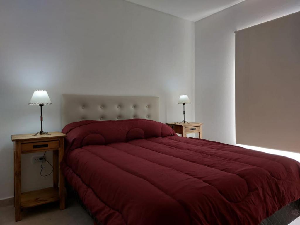 シエラ・デ・ラ・ベンターナにあるALOHAのベッドルーム1室(赤い大型ベッド1台、テーブル2台付)