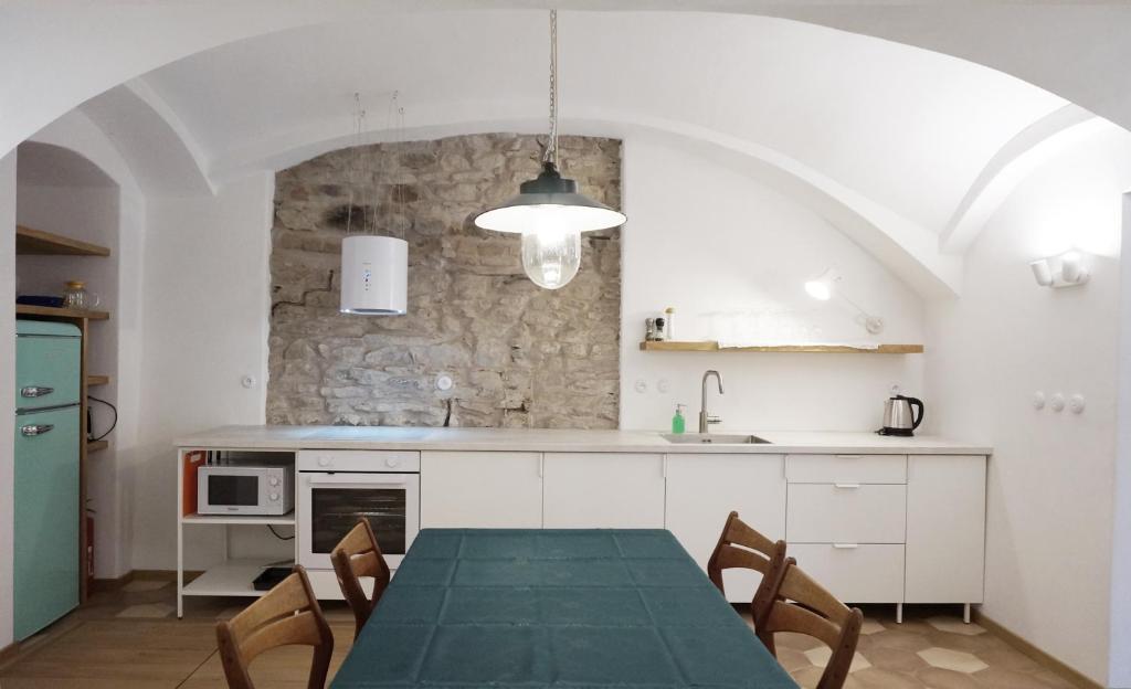 a kitchen with a table and chairs and a stone wall at Old Town Flat with Private Patio in Kutná Hora