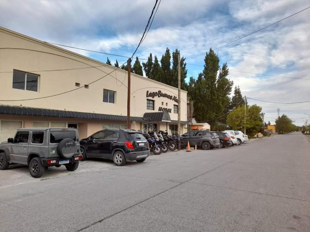 a parking lot with cars parked in front of a building at Lago Buenos Aires in Perito Moreno