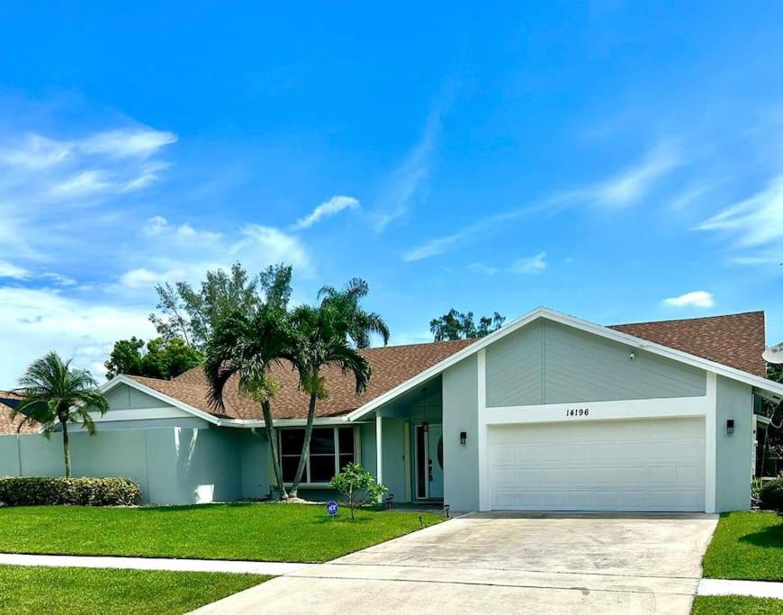 une maison avec un garage et des palmiers dans l'établissement Luxurious pool home in Palm Beach County, Florida, à Wellington