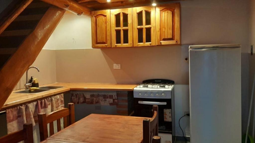 cocina con mesa, fogones y armarios en Complejo turístico Nahuel pan en Esquel