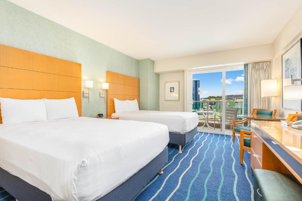 a hotel room with two beds and a balcony at Castle at Ala Moana Hotel in Honolulu