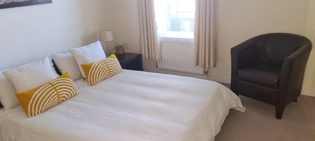 a bedroom with a white bed with pillows and a chair at 2 bed city centre executive apartment in Aberdeen