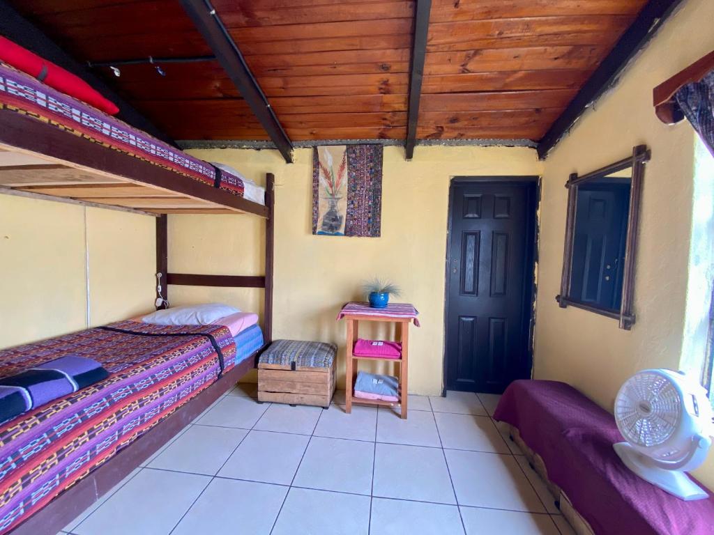 a room with two beds and a table and a door at El Calvario Hostal in Cobán