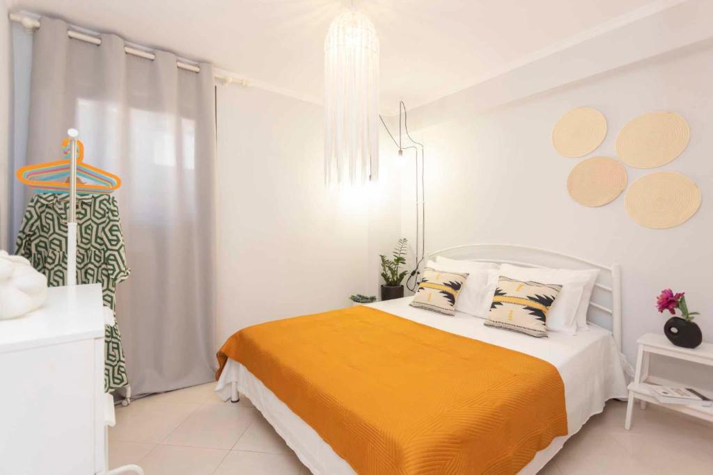 a white bedroom with a bed with a orange blanket at Ikia Apartment Private garden and parking in Pefkohori