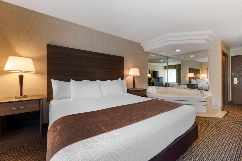 a hotel room with a large bed and a bath tub at Best Western Spooner Riverplace in Spooner