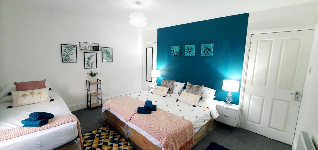 1 dormitorio con 2 camas y pared azul en Stourbridge House, Luxurious 3 Bedrooms - Ideal Location for Contractors and Families, Free Parking, Fast Wifi, Sleeps up to 8 en Lye