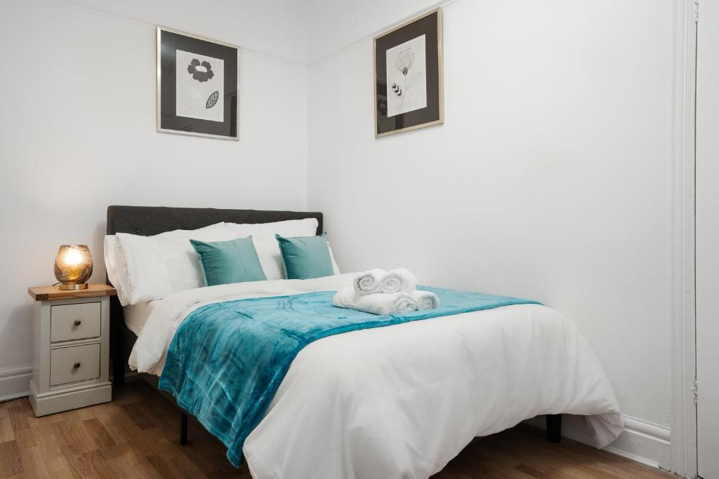 a white bedroom with a bed with a blue blanket at Beautiful Anfield home close to LFC stadium in Liverpool