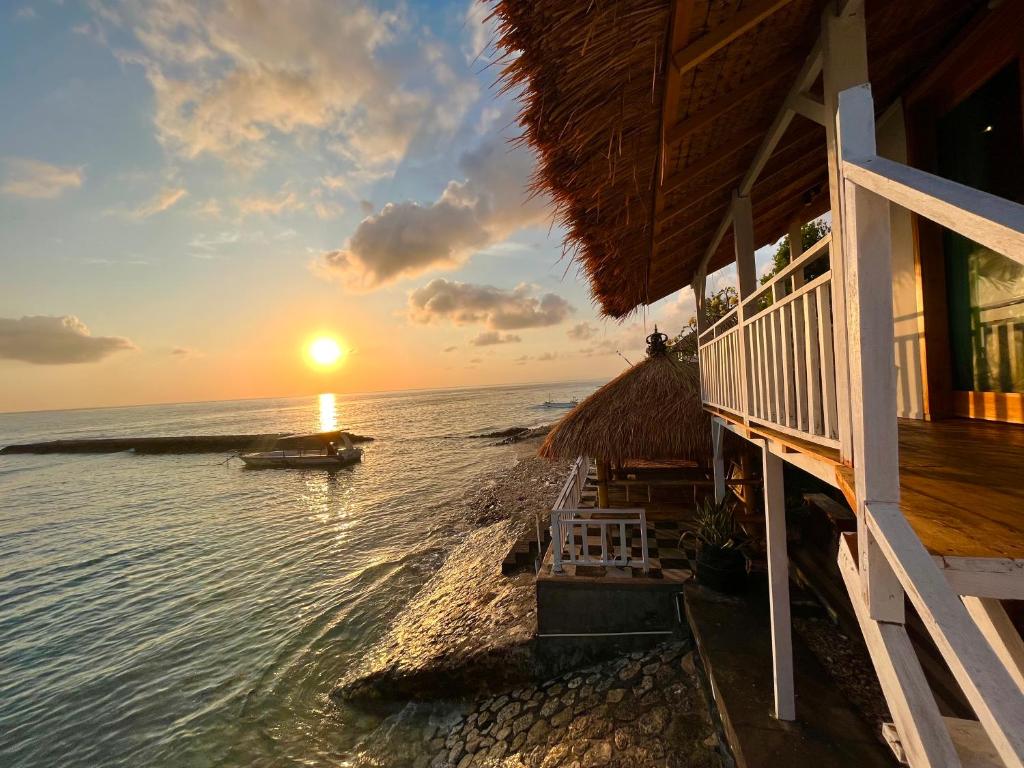 a house on the beach with the sunset in the background at Coastal Inn Penida in Nusa Penida