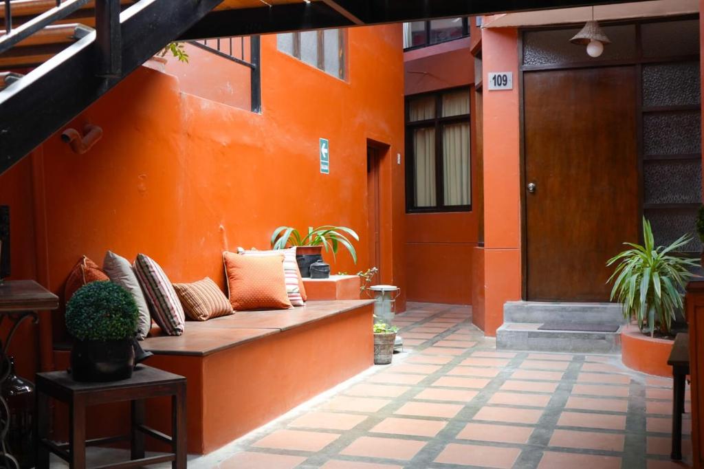 an orange wall with a bench in front of a door at Hotel Pilancones in Cajamarca