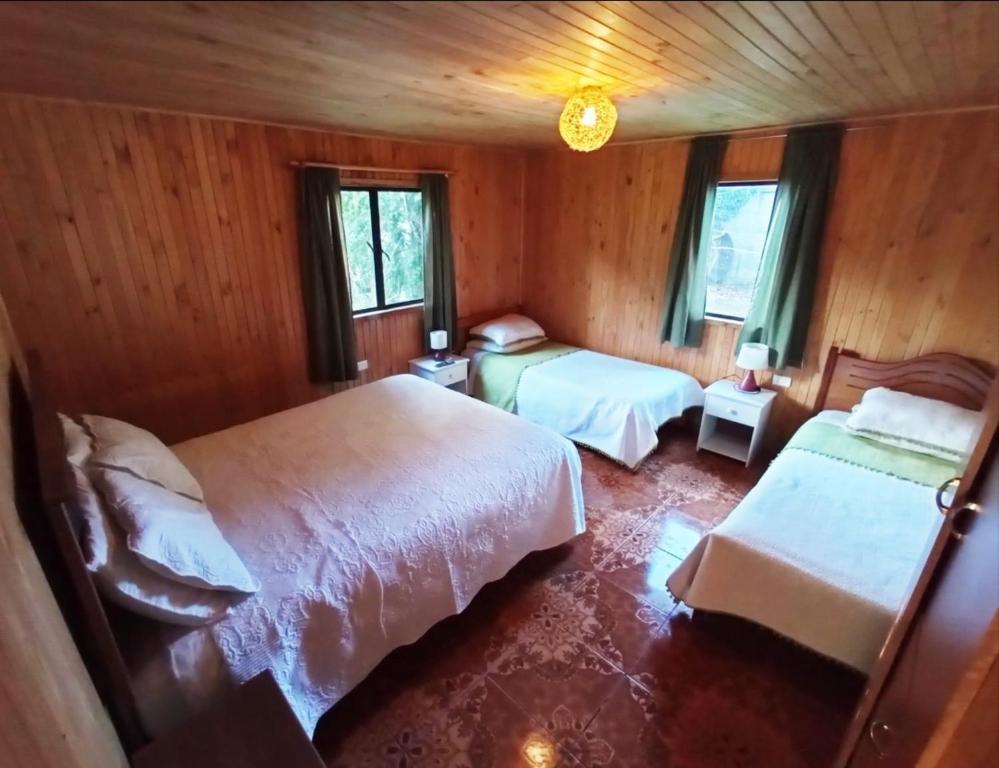 - une chambre avec 2 lits et 2 fenêtres dans l'établissement Hostal Turismo Allipen, à Melipeuco