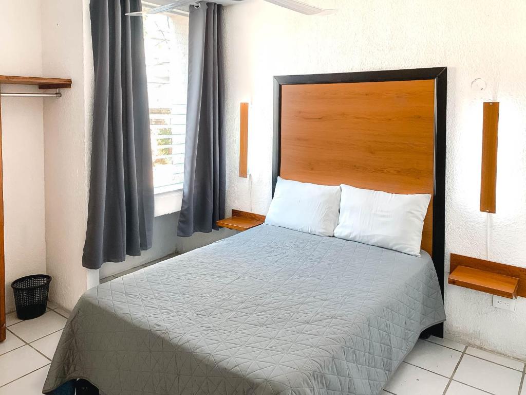 een slaapkamer met een groot bed met een houten hoofdeinde bij Departamentos 1E in Puerto Vallarta