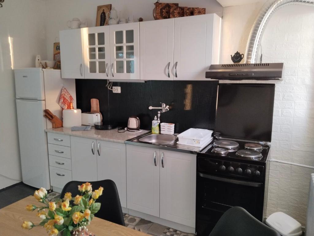 eine Küche mit weißen Schränken und einem schwarzen Herd in der Unterkunft Bagins Apartman in Kostolac