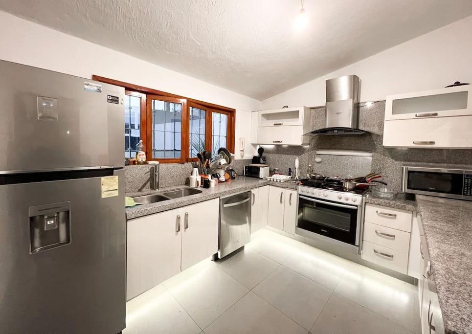 una cocina con armarios blancos y electrodomésticos de acero inoxidable en Casa cerca de Andares, Amplia / Planta Baja @serra, en Guadalajara