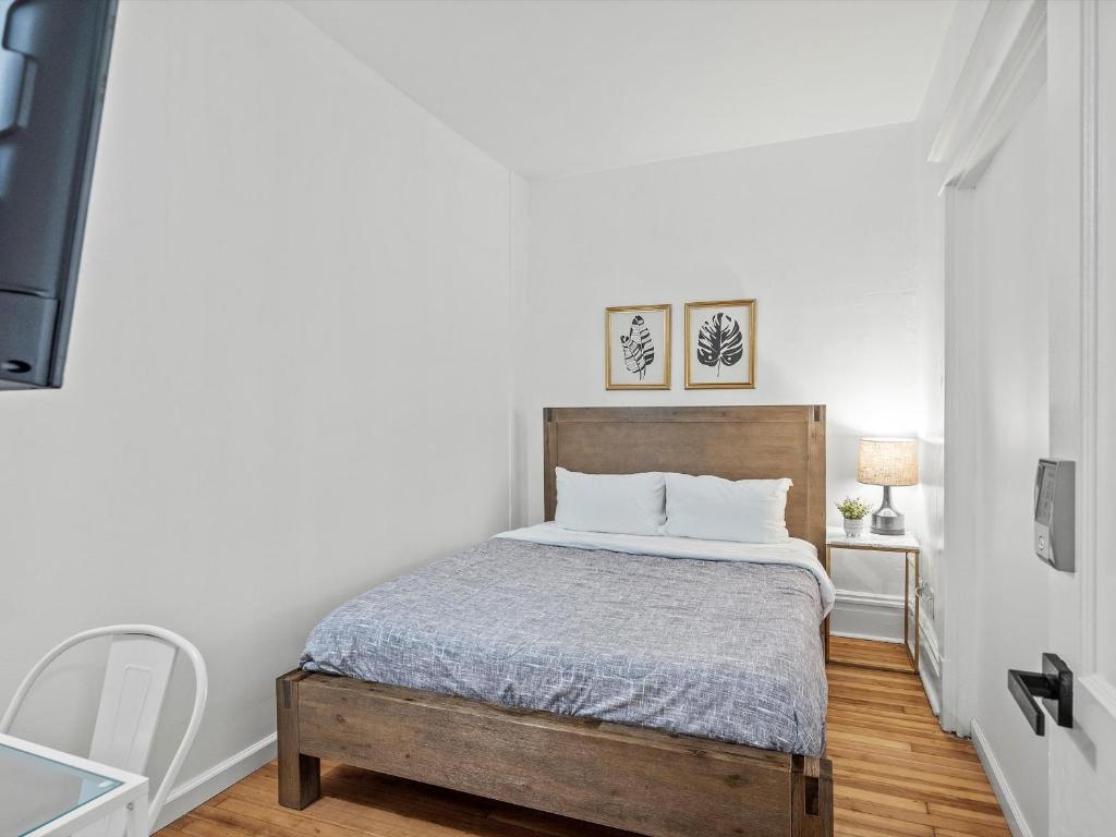 a bedroom with a bed with white walls and wooden floors at Oakland/University @B Quiet & Stylish Private Bedroom with Shared Bathroom in Pittsburgh