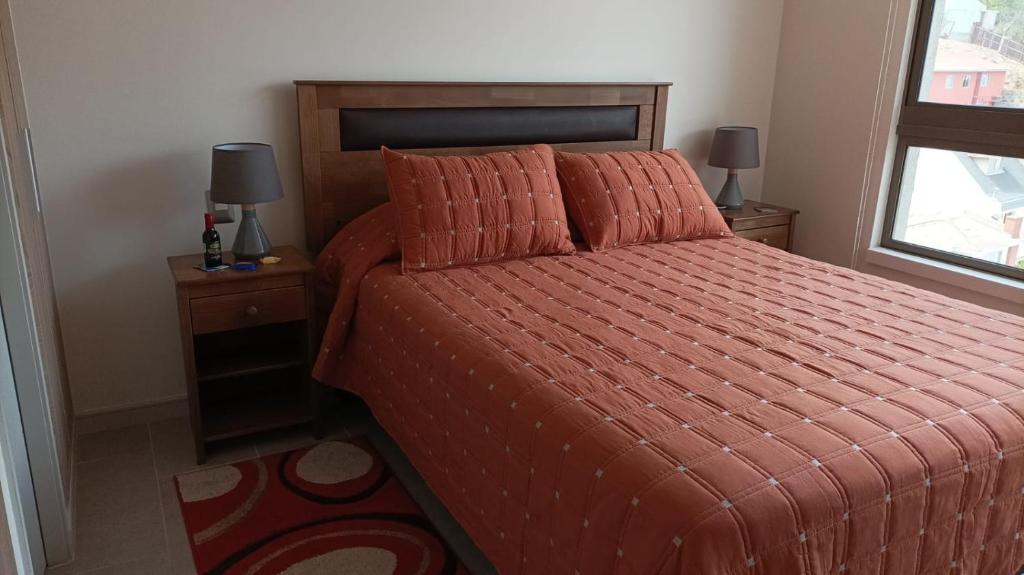 1 dormitorio con 1 cama con edredón de naranja y ventana en Viña Parque Urbano, en Viña del Mar